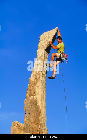 Male rock climber clinging to a cliff. Stock Photo