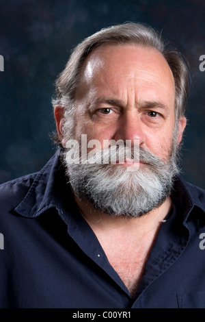 Gray haired bearded man has a serious and somber look. Stock Photo
