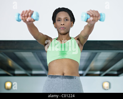 young african american woman in green sportswear doing weight lifting in fitness club. Horizontal shape, front view, waist up Stock Photo