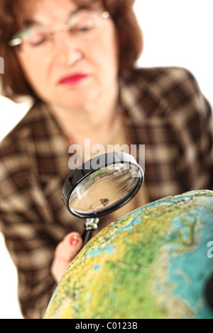 senior teacher holding magnifier and looking the world map selective focus image Stock Photo