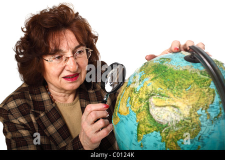 senior teacher holding magnifier and looking the world map Stock Photo