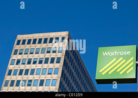 waitrose sign with office building in background on new malden high street, surrey, england Stock Photo