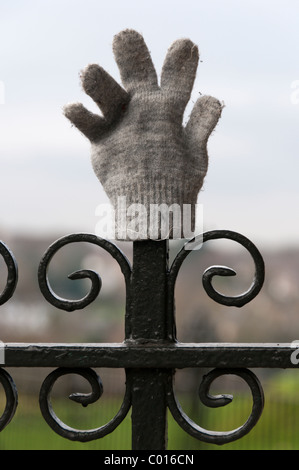 A lost glove placed on park railings. Stock Photo