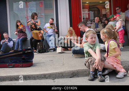 Making music with a violin, an accordion, a guitar and a flute at an Irish music session in the street, music festival Fleadh Stock Photo