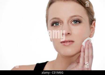 Blonde woman removing make up with cotton wool pad Stock Photo