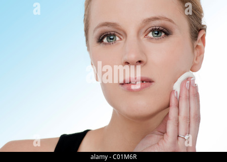 Blonde woman removing make up with cotton wool pad Stock Photo