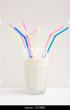 Glass of milk with several straws, distribution Stock Photo
