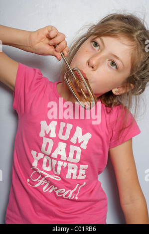 Young girl licking chocolate icing from whisk Stock Photo