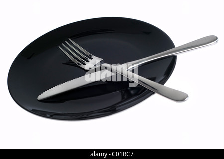 Empty black plate with knife and fork on white background Stock Photo