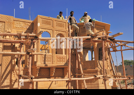 Craftsmen working on a simple wooden frame with knotted ropes on an ornate sandstone facade, Jaisalmer, Rajasthan, India, Asia Stock Photo