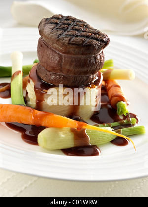 Steak tournedo on dauphinoise potatoes with baby carrots baby leeks and sauce Stock Photo