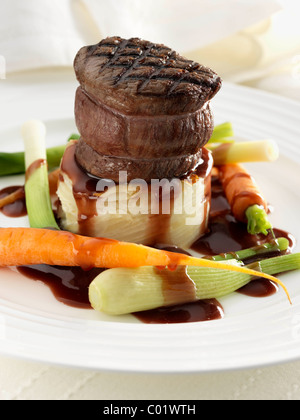 Steak tournedo on dauphinoise potatoes with baby carrots baby leeks and sauce Stock Photo