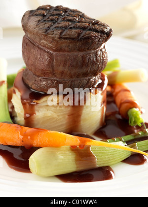 Steak tournedo on dauphinoise potatoes with baby carrots baby leeks and sauce Stock Photo