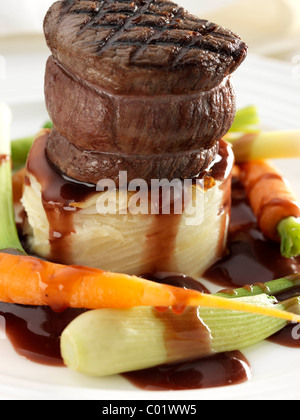 Steak tournedo on dauphinoise potatoes with baby carrots baby leeks and sauce Stock Photo