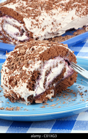 Chocolate swiss roll cake with berries marmalade and whipped cream over a chequered background Stock Photo