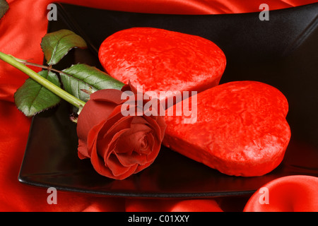 Two red heart shaped cakes on a black plate over a red background for Valentine's Day Stock Photo