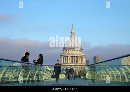 Pedestrians on Millennium Bridge, crossing the River Thames, taken from Bankside looking to St Pauls Cathedral,  London, England Stock Photo