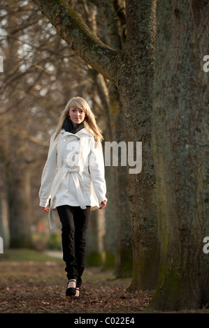 A slim blonde 14 year old teenage girl outdoors walking in a park on am autumn day, UK Stock Photo
