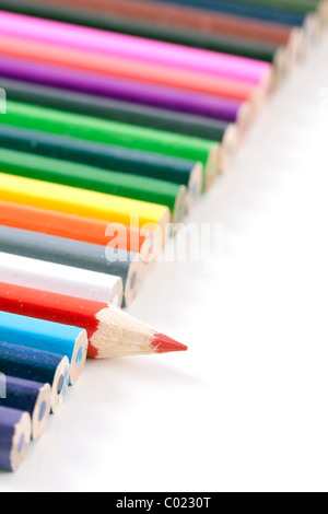 Row of color full pencils with one different pencil which sticks out of the mass with a small depth of field Stock Photo
