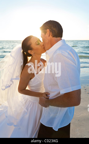 Married couple, bride and groom, kissing at sunset on a beautiful tropical beach wedding Stock Photo