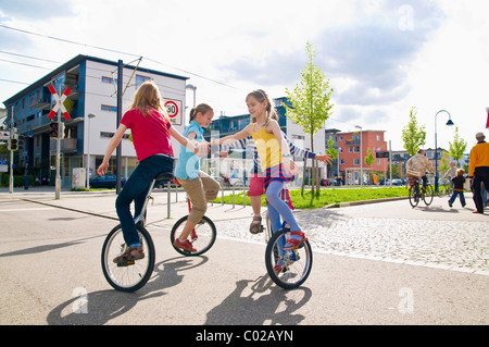 Children on unicycles in a play street, Vauban district in Freiburg im Breisgau, Baden-Wuerttemburg, Germany, Europe Stock Photo