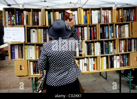Elderly lady taking a thick novel from store shelf, open-air book market, Koenigsallee, Duesseldorf, North Rhine-Westphalia Stock Photo