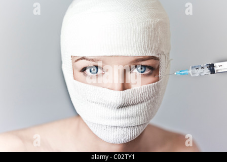 a woman with her head wrapped in a bandage and syringe Stock Photo