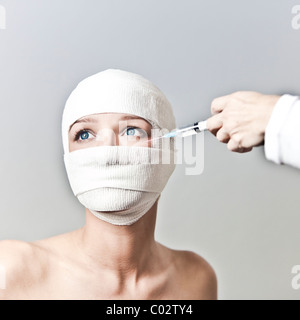 a woman with her head wrapped in a bandage and syringe Stock Photo