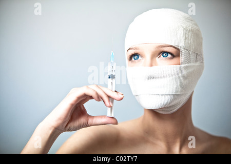 a woman with her head wrapped in a bandage and syringe Stock Photo