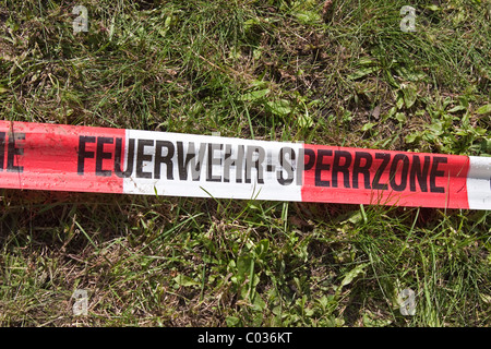 Red and white barrier tape, fire tape, labelled Feuerwehr-Sperrzone, German for fire brigade exclusion zone Stock Photo