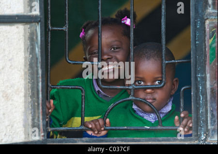Boy and girl, 4-5 years, looking through barred windows, African children, portrait, Tanzania, Africa Stock Photo