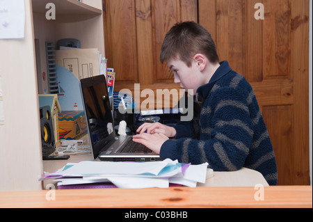 A MODEL RELEASED picture of an eleven year old boy doing homework on his laptop computer in his bedroom Stock Photo