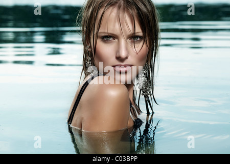 Young woman in a black bathing suit and with wet hair, bathing in a lake Stock Photo