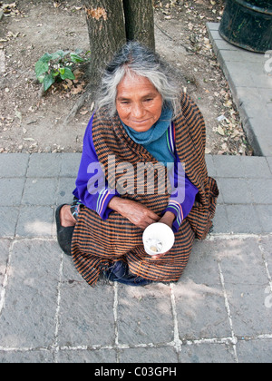 old Mexican indian woman wearing clean clothes sits on pavement begging at entrance to Chapultepec Park Mexico City Mexico Stock Photo