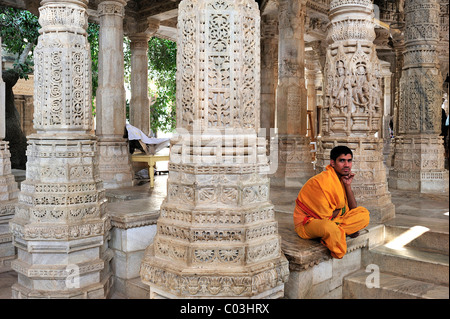 Young monk wearing the traditional yellow monk's robe in the inner hall with ornate marble pillars in the Temple of Ranakpur Stock Photo