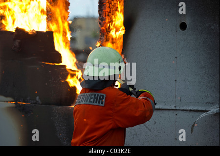 Fireman in front of a burning wall Stock Photo