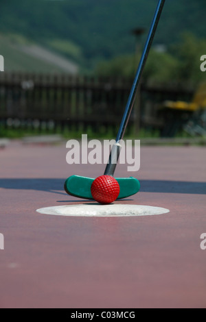 Mini golf, golf club just about to putt a ball in a hole, Germany Stock Photo