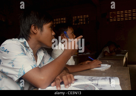 A young boy who is a school student is pointing during an English lesson at an elementary school in rural Cambodia. Stock Photo