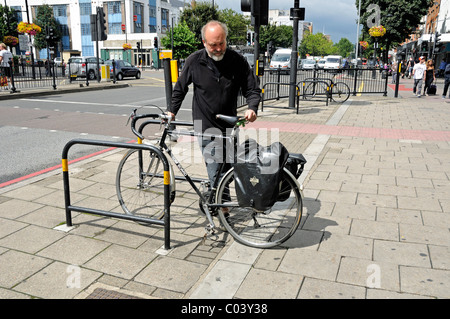 Man unlocking bike from cycle rack in Holloway Road Islington London England UK Stock Photo