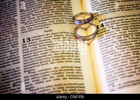two wedding rings on a bible creating a shadow of love Stock Photo
