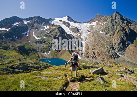 A hiker stands in front of the Grausee, Wilder Freiger glacier, and Cima Libera on the Stubai Hohenweg in Tyrol, Austria. Stock Photo