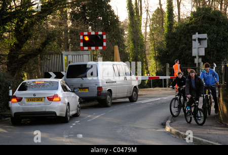 Railway employee in reflective safety clothing at a single barrier level crossing near Petersfield Hampshire England UK Boys on Stock Photo