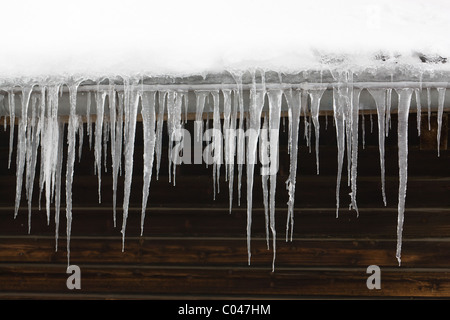 roof covered with snow, long icicles hanging on the rainwater gutter Stock Photo
