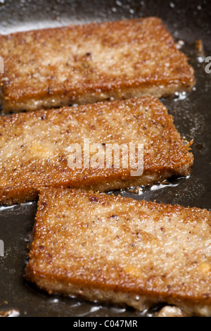 Slices of scrapple frying in a skillet Stock Photo