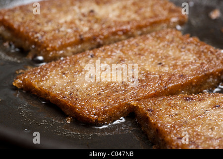 Slices of scrapple frying in a skillet Stock Photo