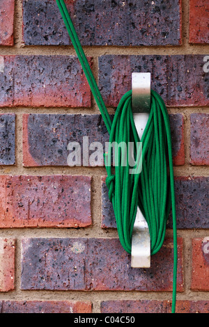 Green rope wrapped around a wall mounted cleat. Stock Photo