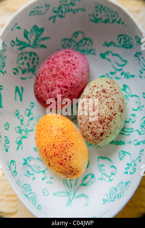 Three candy covered chocolate mini easter eggs in egg shaped box  with easter themed images inside. Stock Photo