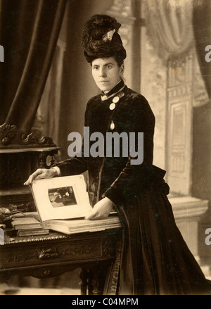 Victorian Woman Looking Through a Photograph Album of Family Photographs c1880. Vintage Cabinet Card Stock Photo