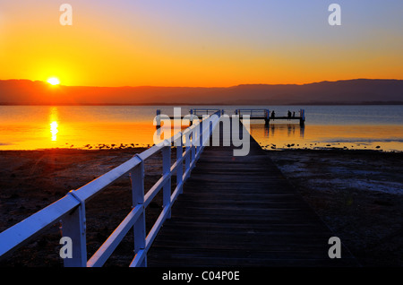 A woman on a jetty in Lake Illawarra watching the sunset