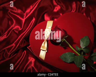 Red heart-shaped gift box and a red rose Stock Photo